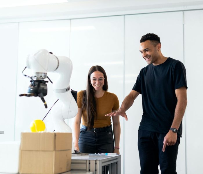 Two engineers collaborating on testing a futuristic robotic prototype in a modern indoor lab.